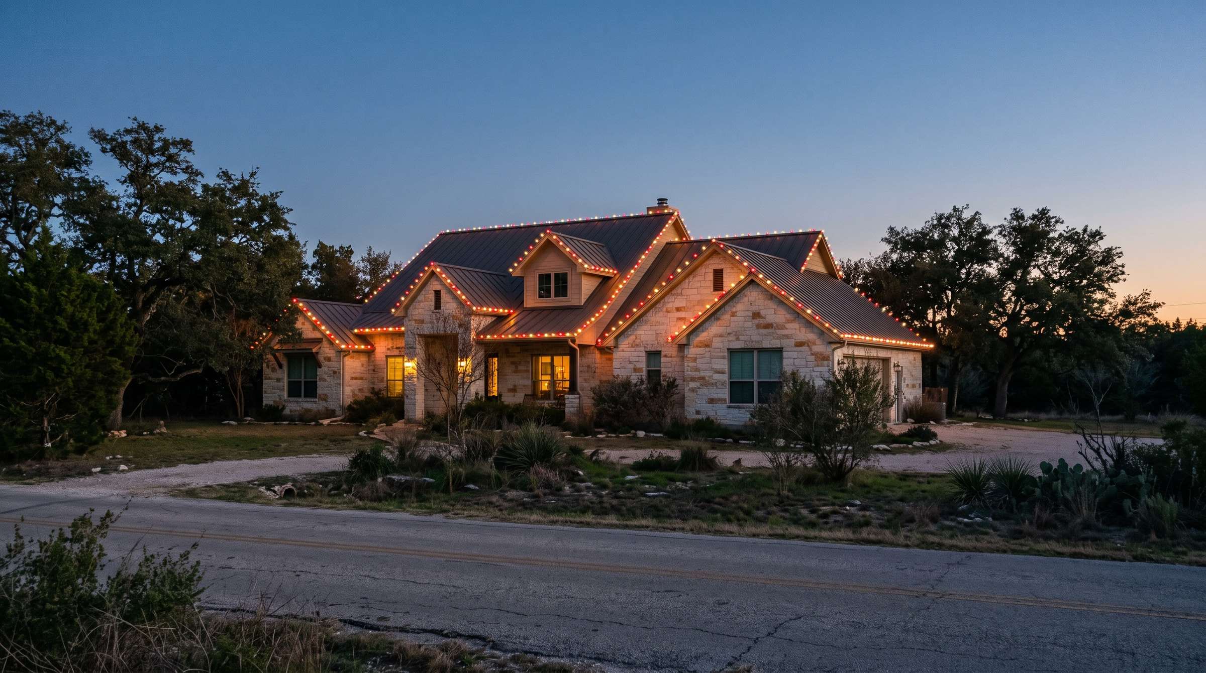 Stone home with a roofline of alternating red and warm white C9 bulbs and a wreath with a red bow